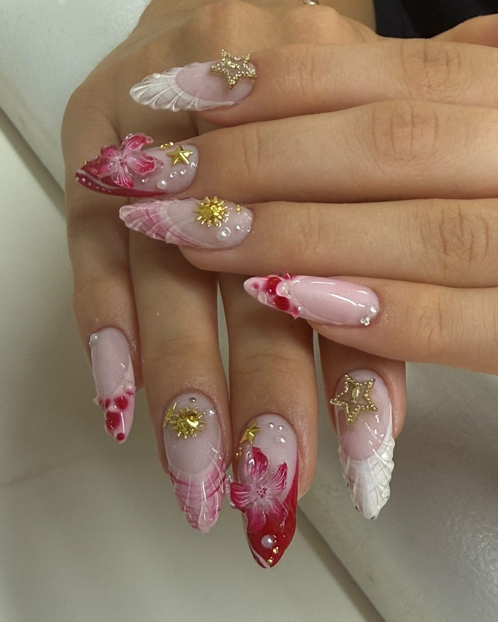 Mandelnägel mit handgemalten roten Blüten, weißen 3D-Details und goldenen Sternen im Nagelstudio D&T Nails in Köln
